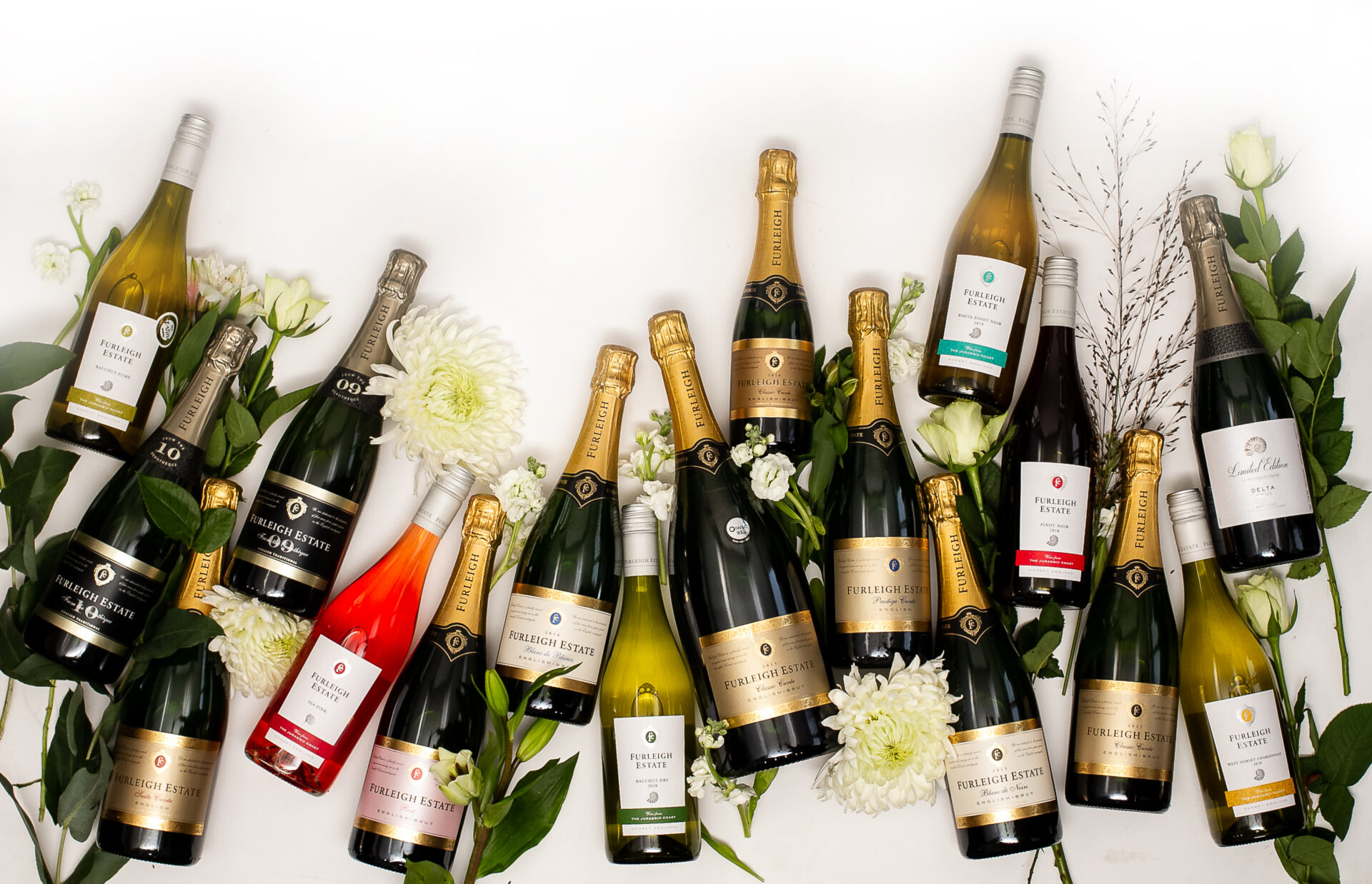 A spread of Furleigh Estate sparkling and still wines on a white table with white flowers.