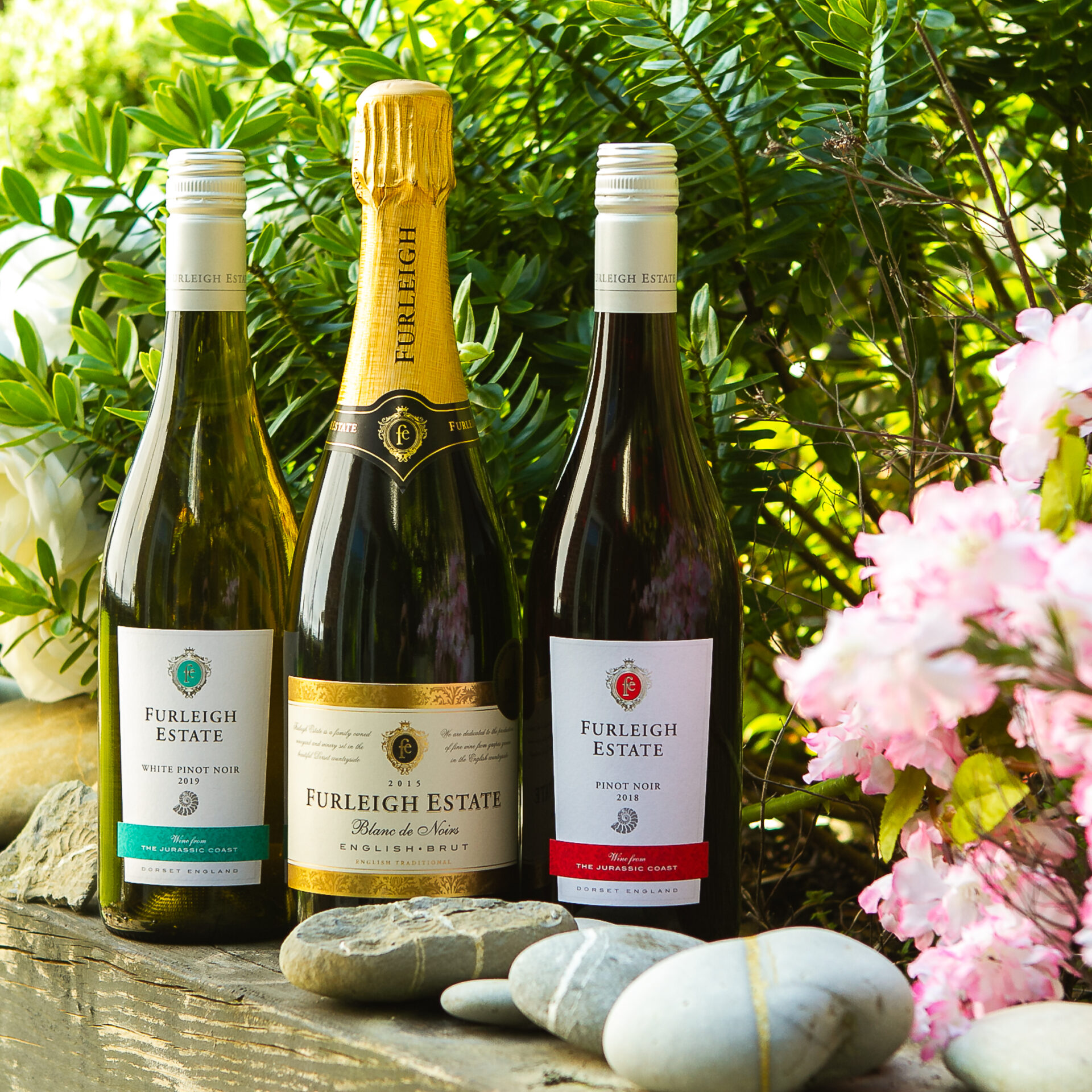 Three bottles of Furleigh Estate wines in a scenic garden photo