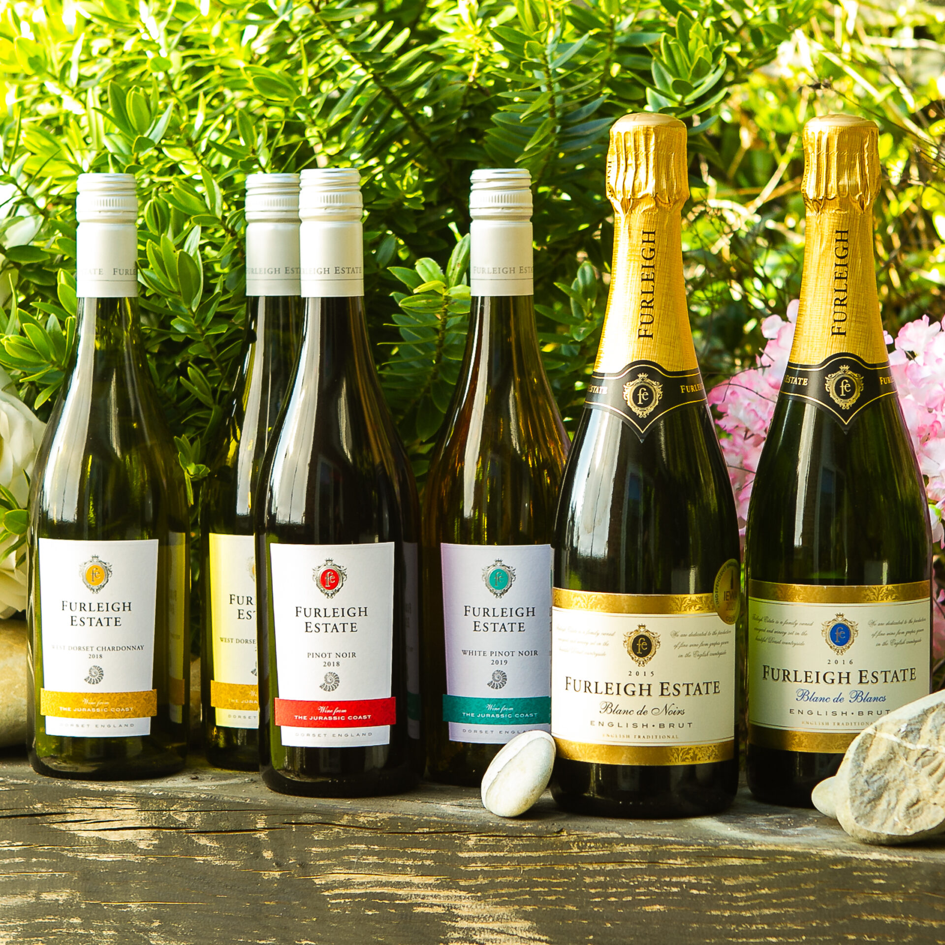 Six bottles of Furleigh Estate wines in a scenic garden photo